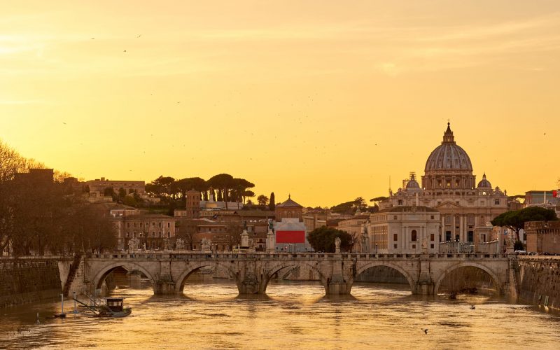 St. Peter's cathedral and Tiber river with high water at  sunset. Saint Peter Basilica in Vatican city with Saint Angelo Bridge in Rome, Italy