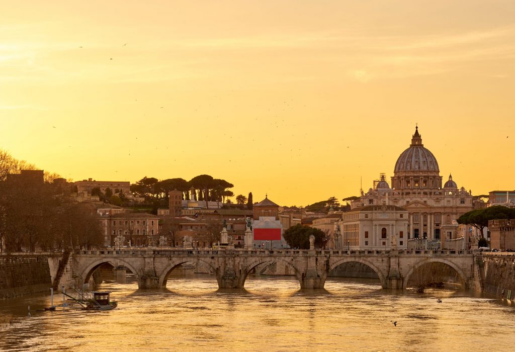 St. Peter's cathedral and Tiber river with high water at  sunset. Saint Peter Basilica in Vatican city with Saint Angelo Bridge in Rome, Italy
